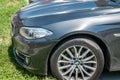 Headlight hood and tire of black BMW series 7 car parked on the street. Royalty Free Stock Photo