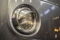 The headlight of an old hippie minibus, the front of a stylish old camper, a stylish visor over the headlight