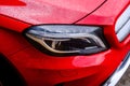 Headlight of a red Mercedes Benz GLA with dew on it