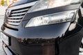 Headlight of Toyota Vellfire japanese luxury minivan car in black color on the parking with seven passenger seats Royalty Free Stock Photo