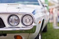 Headlights of old white american muscle car with chrome bumper