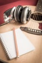 Headphone and Notebook and pencil on guitar