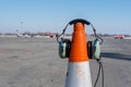 Headphones of aircraft technician, who conducts preflight preparation of the aircraft, are put on an orange cone