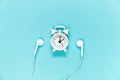 Headphones and alarm clock on a blue background. Musical concept. Top view with copy space