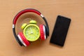 Headphones and alarm clock and smartphone on wooden desk. Musical concept