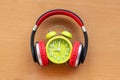Headphones and alarm clock on wooden desk. Musical concept