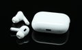 Headphones Apple Air Pods Pro 2 with Wireless Charging Case on black background. AirPods are wireless Bluetooth earbuds designed Royalty Free Stock Photo
