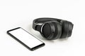Headphones with Bluetooth technology on white background, with black phone paired for music lovers Royalty Free Stock Photo