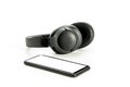 Headphones with Bluetooth technology on white background, with black phone paired for music lovers Royalty Free Stock Photo