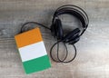 Headphones and book. The book has a cover in the form of Ivory Coast flag.