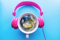 Headphones and coffee cup on blue background table. Music concept. Earth globe inside. Top view with copy space Royalty Free Stock Photo