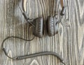 Headphones with cord lying on wooden background.