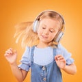 Headphones, dancing or child streaming music to relax with freedom in studio on orange background. Hair, moving or girl Royalty Free Stock Photo