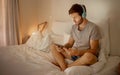 Headphones, digital tablet and in bed watching online movies, videos or series at night in house bedroom. Man on