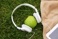 Headphones, electronic tablet and green apple for picnic in park