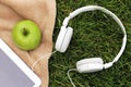 Headphones, electronic tablet and green apple for picnic in park