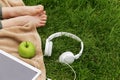 Headphones, electronic tablet and green apple for picnic in park