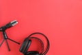 Headphones and microphone on red background. Concept music or podcast. Top view, flat lay Copy space