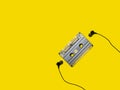Headphones and old audio cassette on yellow background Royalty Free Stock Photo