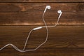 Headphones resting on table top. Headphones with white cable. Modern device for listening music. Sound earphones lying on wooden