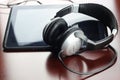 Headphones on a table next to the tablet and a clock Royalty Free Stock Photo