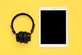 Headphones, white tablet with black screen isolated on yellow background Top view Flat lay Listening to music online, audio books Royalty Free Stock Photo