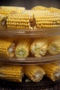 Heads of corn laid out for cooking in a double boiler. Corn broken into pieces in a steamer.