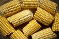 Heads of corn laid out for cooking in a double boiler. Corn broken into pieces in a steamer.