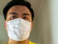 Headshot of Asian Chinese man / person wearing a surgical face mask as protection against contagious diseases