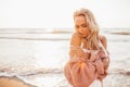 Headshot of beautiful blonde slim girlwearing white dress and cardigan on beach of sea or ocean against the sun. Youth Royalty Free Stock Photo