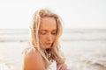 Headshot of beautiful blonde slim girlwearing white dress and cardigan on beach of sea or ocean against the sun. Youth Royalty Free Stock Photo