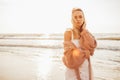 Headshot of beautiful blonde slim girlwearing white dress and cardigan on beach of sea or ocean against the sun. Youth Royalty Free Stock Photo