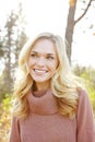 Headshot of a beautiful blonde woman standing in a park in fall. Happy attractive young female smiling outside on an Royalty Free Stock Photo