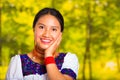 Headshot beautiful young woman wearing traditional andean blouse with red necklace, posing for camera touching face Royalty Free Stock Photo