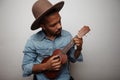 Headshot of young handsome man playing ukulele posing over white background.