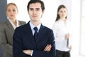 Headshot of businessman standing straight with colleagues at background in office. Group of business people discussing