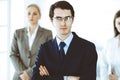 Headshot of businessman standing straight with colleagues at background in office. Group of business people discussing