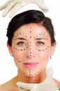 Headshot caucasian woman with dotted lines drawn around face looking into camera, doctors hands holding her head Royalty Free Stock Photo