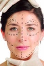 Headshot caucasian woman with dotted lines drawn around face looking into camera, doctors hands holding her head Royalty Free Stock Photo