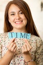 Headshot charming brunette woman holding up small letters spelling the word time and smiling to camera Royalty Free Stock Photo