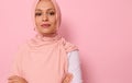 Headshot, close-up face portrait of beautiful Arabic Muslim woman in pink hijab posing looking to camera with attractive gaze,