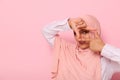 Close-up face portrait of a young Muslim pretty woman of Arabic ethnicity, wearing hijab and looking at the camera through a