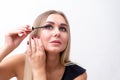 Headshot of female with bright makeup applying mascara on eyelashes. Royalty Free Stock Photo