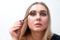 Headshot of female with bright makeup applying mascara on eyelashes. Royalty Free Stock Photo