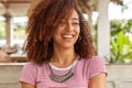 Headshot of funny black woman with curly hair, laughs at good joke, has toothy smile, shows white perfect teeth, wears