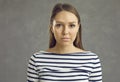 Studio portrait of young woman looking at camera with serious unemotional expression