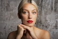 Headshot of blond haired woman wearing red lipstick while standing at isolated grey background Royalty Free Stock Photo