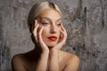 Headshot of blond haired woman wearing red lipstick while standing at isolated grey background Royalty Free Stock Photo