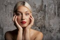 Headshot of blond haired woman wearing red lipstick while standing at isolated grey background Royalty Free Stock Photo