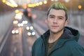 Headshot of handsome green haired guy smiling in the city